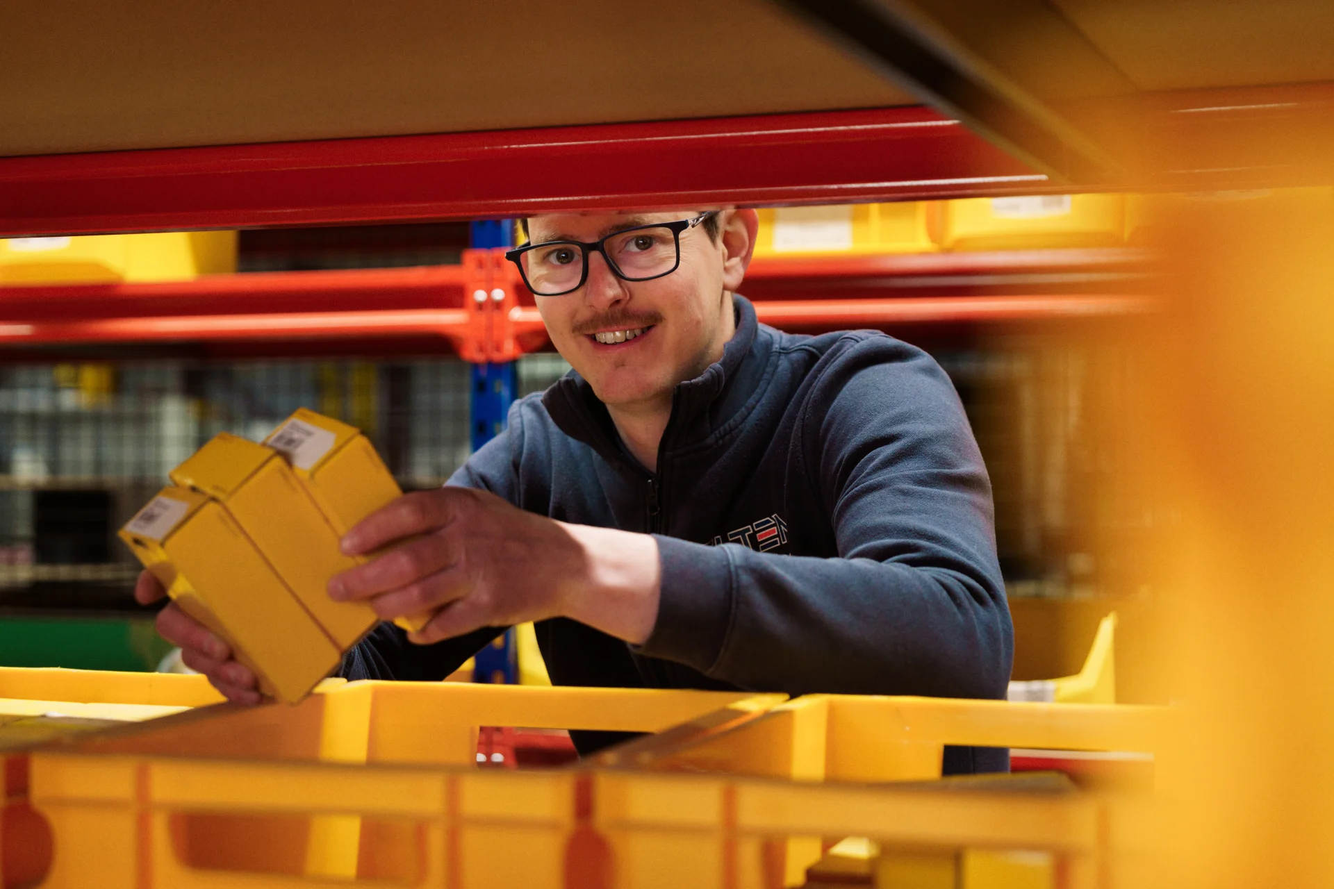 Collega met gele kratten in een stellingsysteem