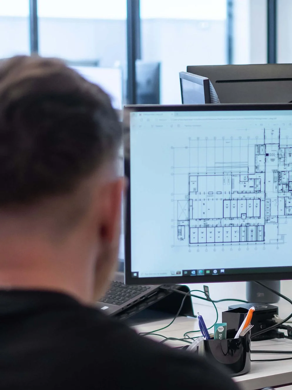 Medewerker bekijkt een technische tekening op een beeldscherm.