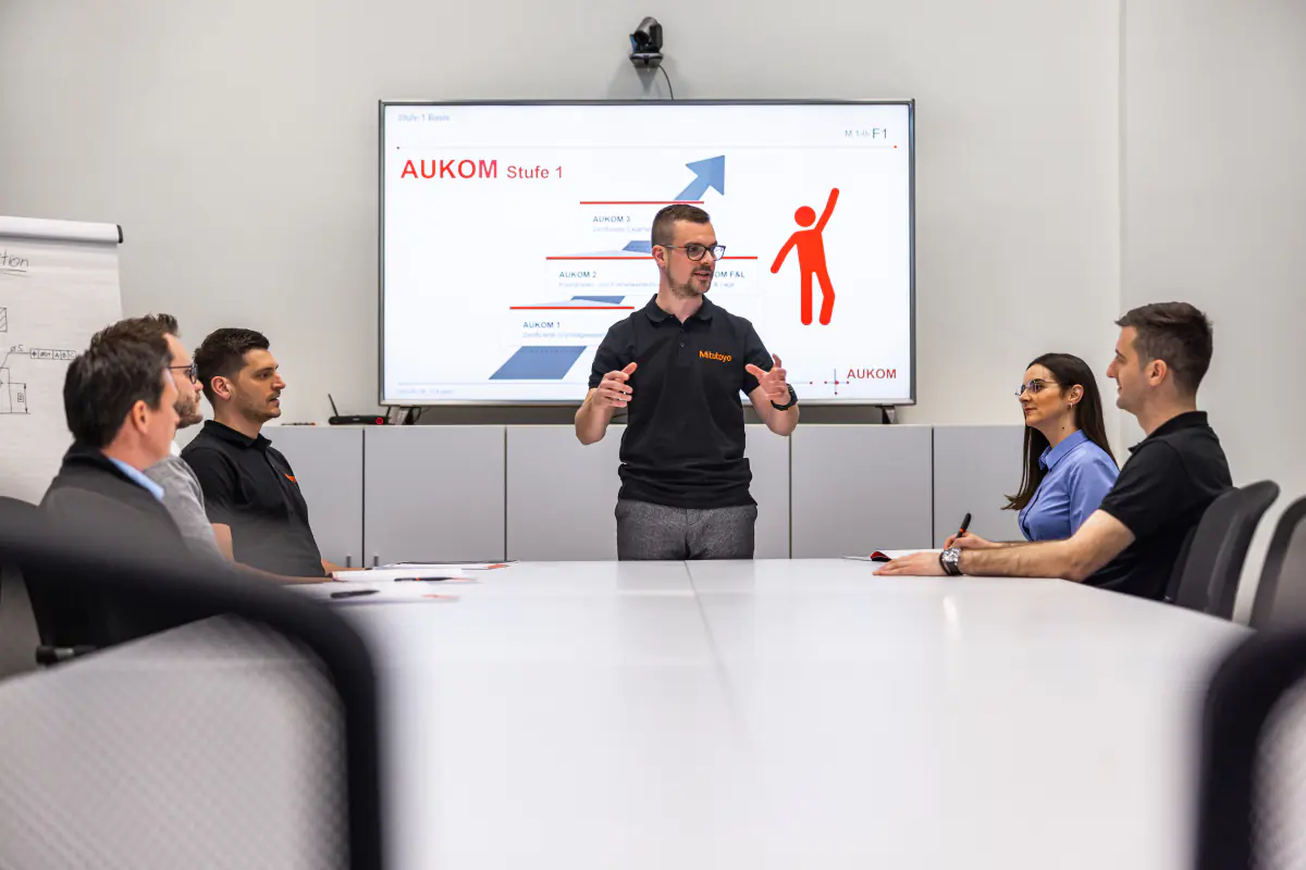 Medewerker geeft een presentatie aan collega's (bron: mitutoyo.eu, Werken bij)