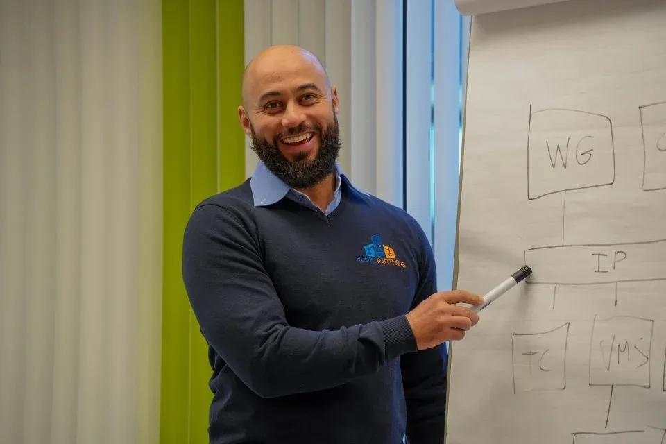 Medewerker van Regel Partners licht een schema toe op een flip-over (bron: inqube.nl/regel-partners)